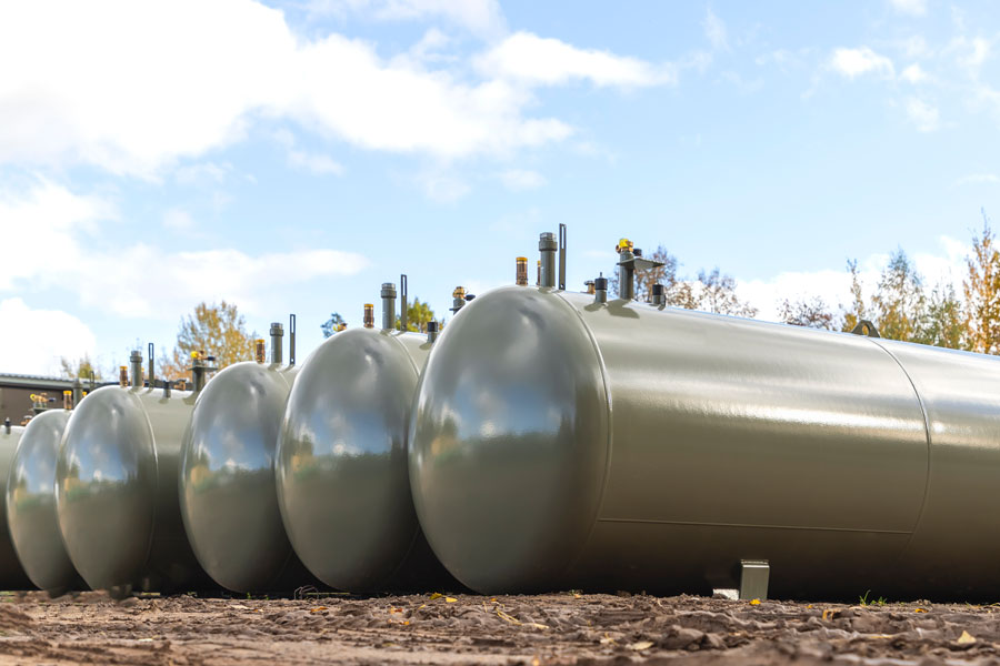 Row of large steel underground storage tanks used for fuel and oil, shown above ground to illustrate the type of tanks removed during UST excavation and decommissioning